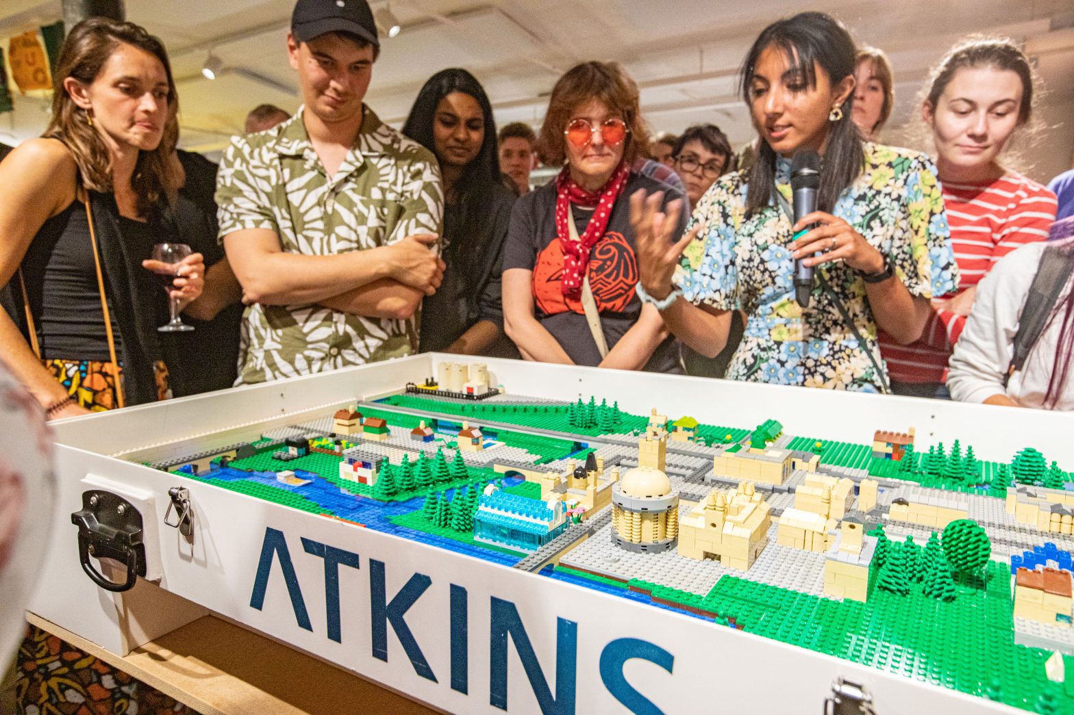 A group of people standing around a large lego model of the city of Oxford. Writing on the walls of the lego model read "Atkins"