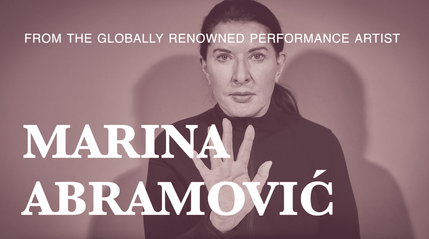 Photo of Marina Abramovic with her palm held up facing outwards. Text over the image reads 'From the globally renowned performance artist Marina Abramovic'