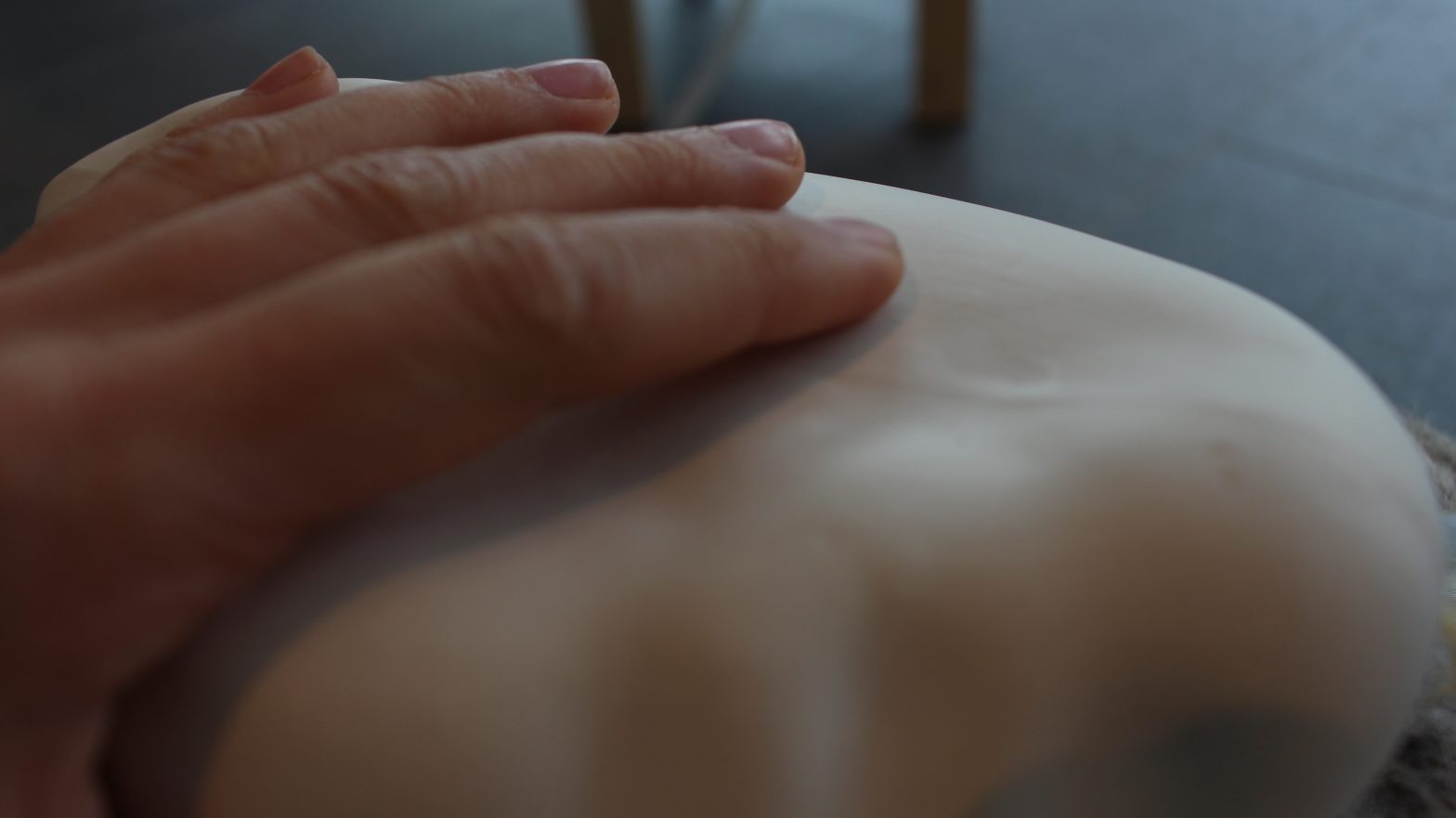 Image of a hand resting upon a white organic sculptural form