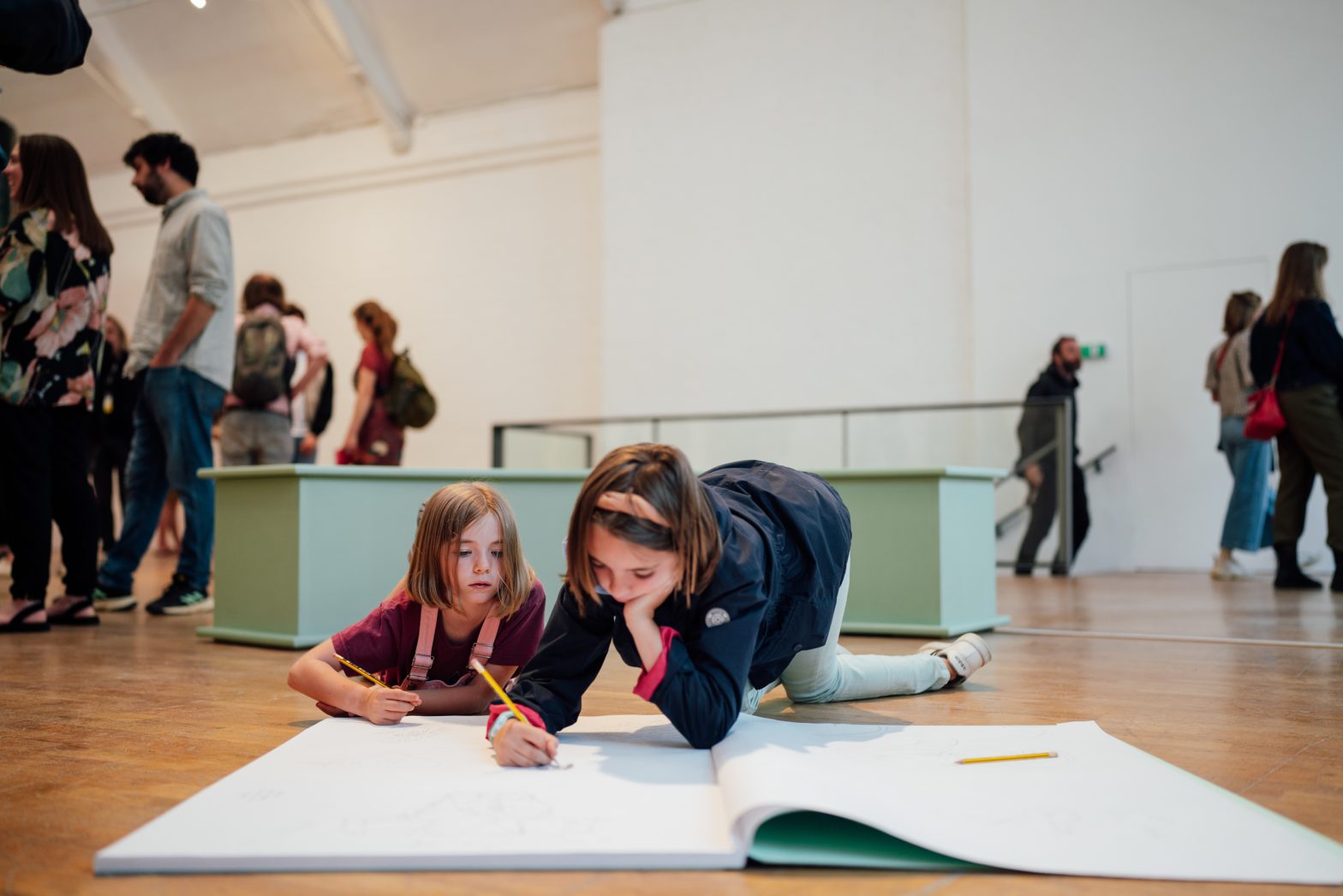 Two children drawing in a large sketchbook.