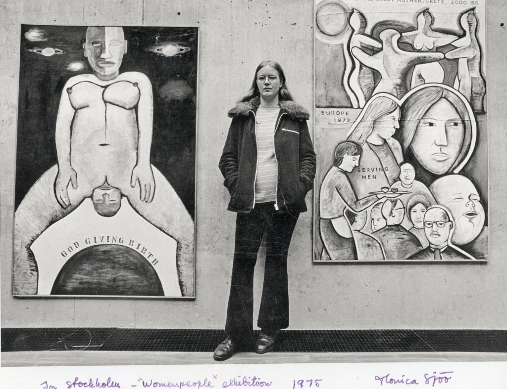 Monica Sjöö stands in front of two of her paintings at an exhibition in Stockholm. 