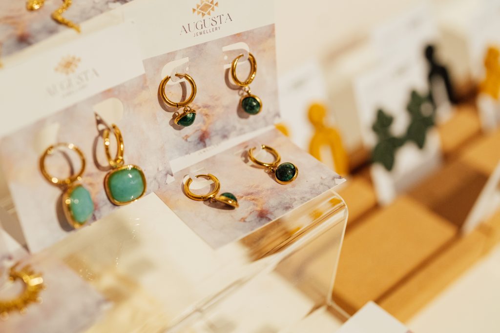 Photograph of gold hoop earrings with large, green gems.