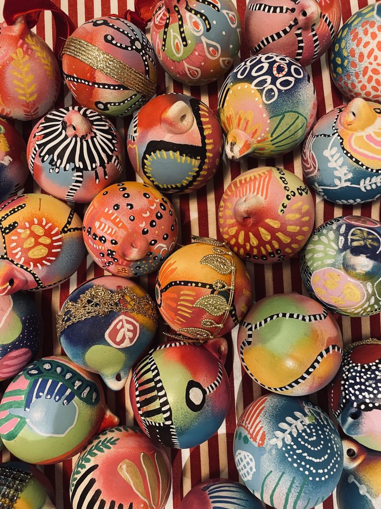 Brightly coloured painted baubles on a red and white striped table cloth.