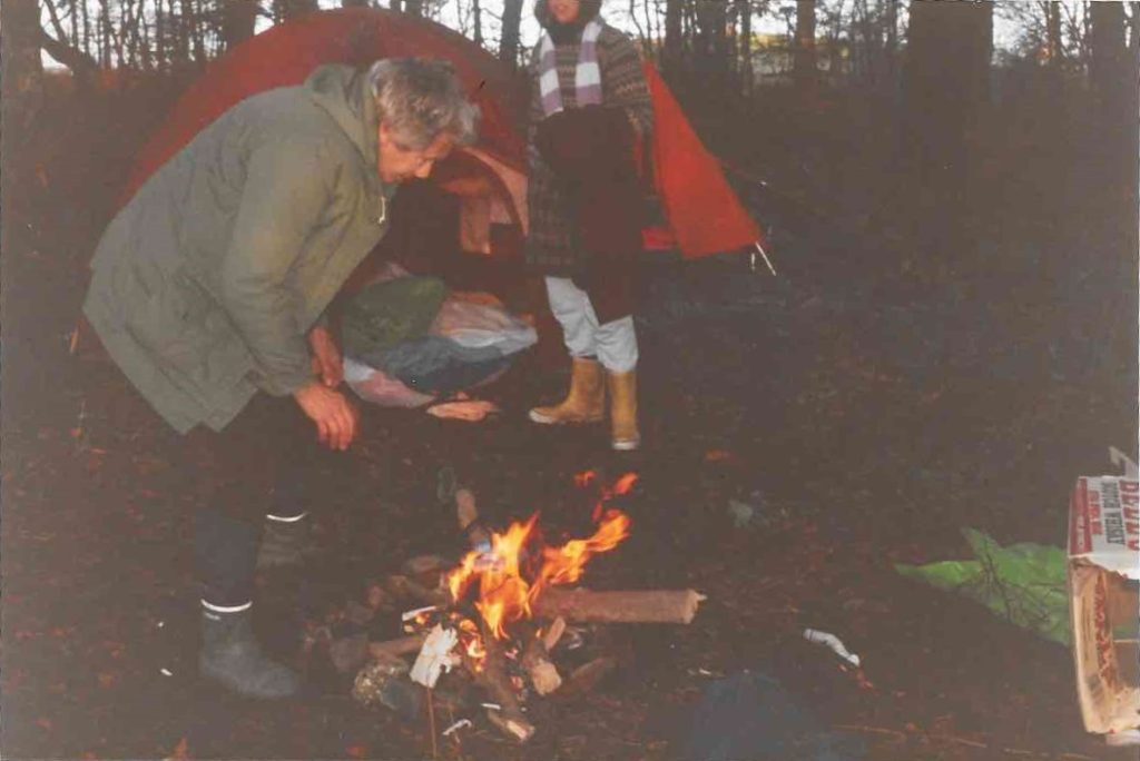 Two women bend over a campfire at Green Gate in the Greenham Common Peace Camp.