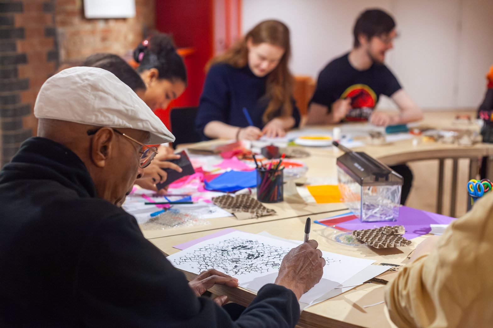 A group of people of varying ages draw together at a round table.