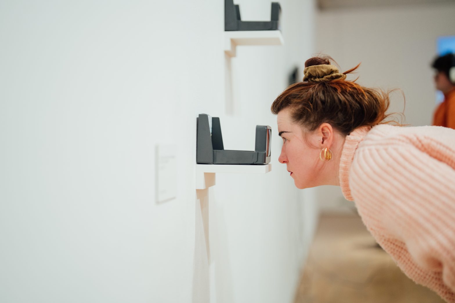 A woman leans over to examine an artwork