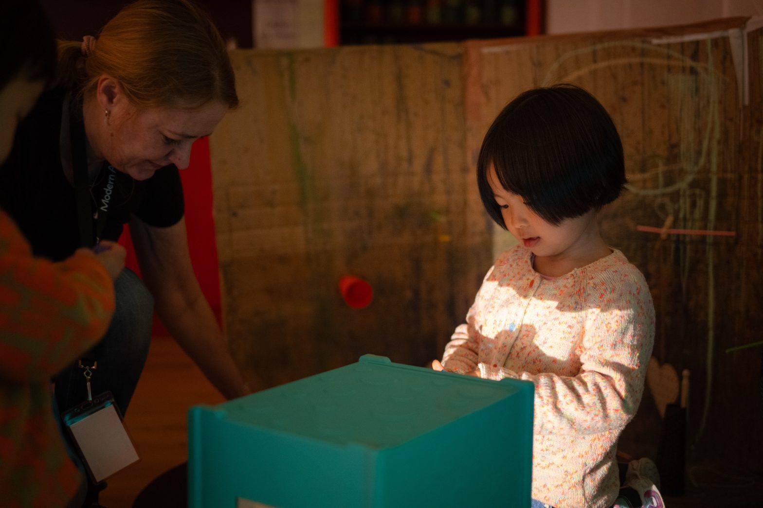 A child looks at a green cube.