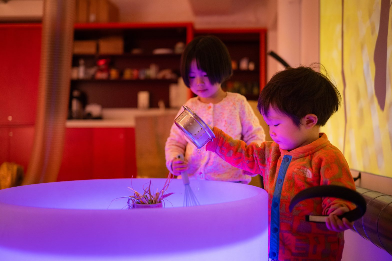 Two children lean over a sandbox
