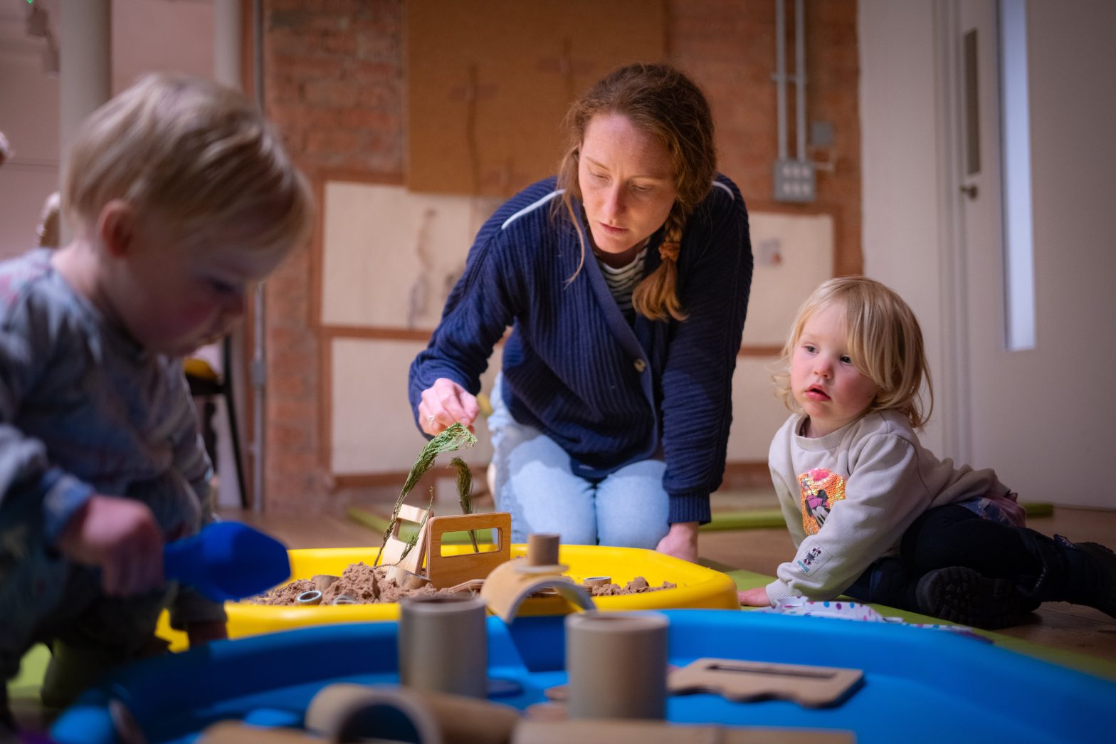 A mother plays with her two young children.