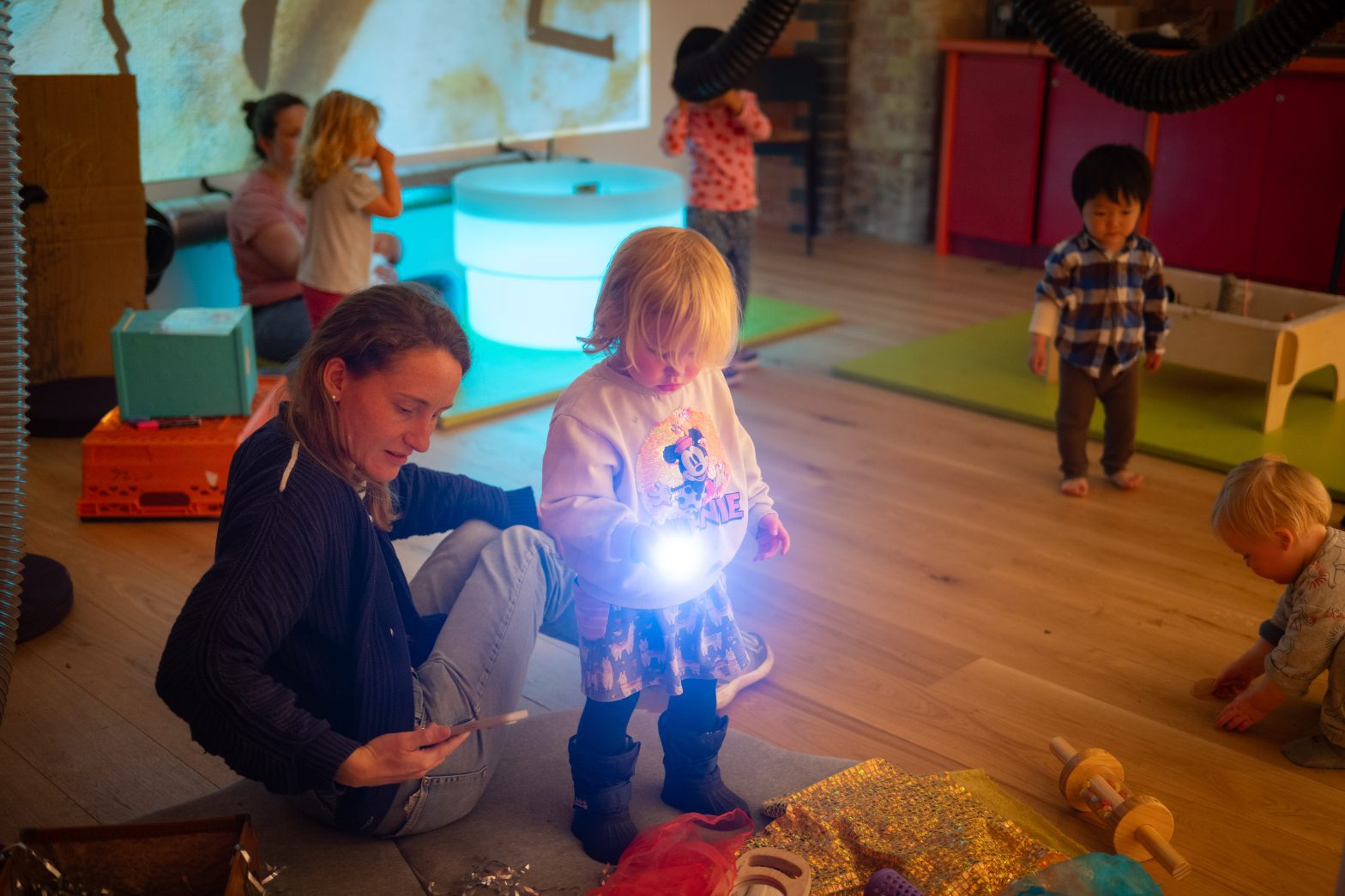 A mother and child shine a torch as they view an artwork.