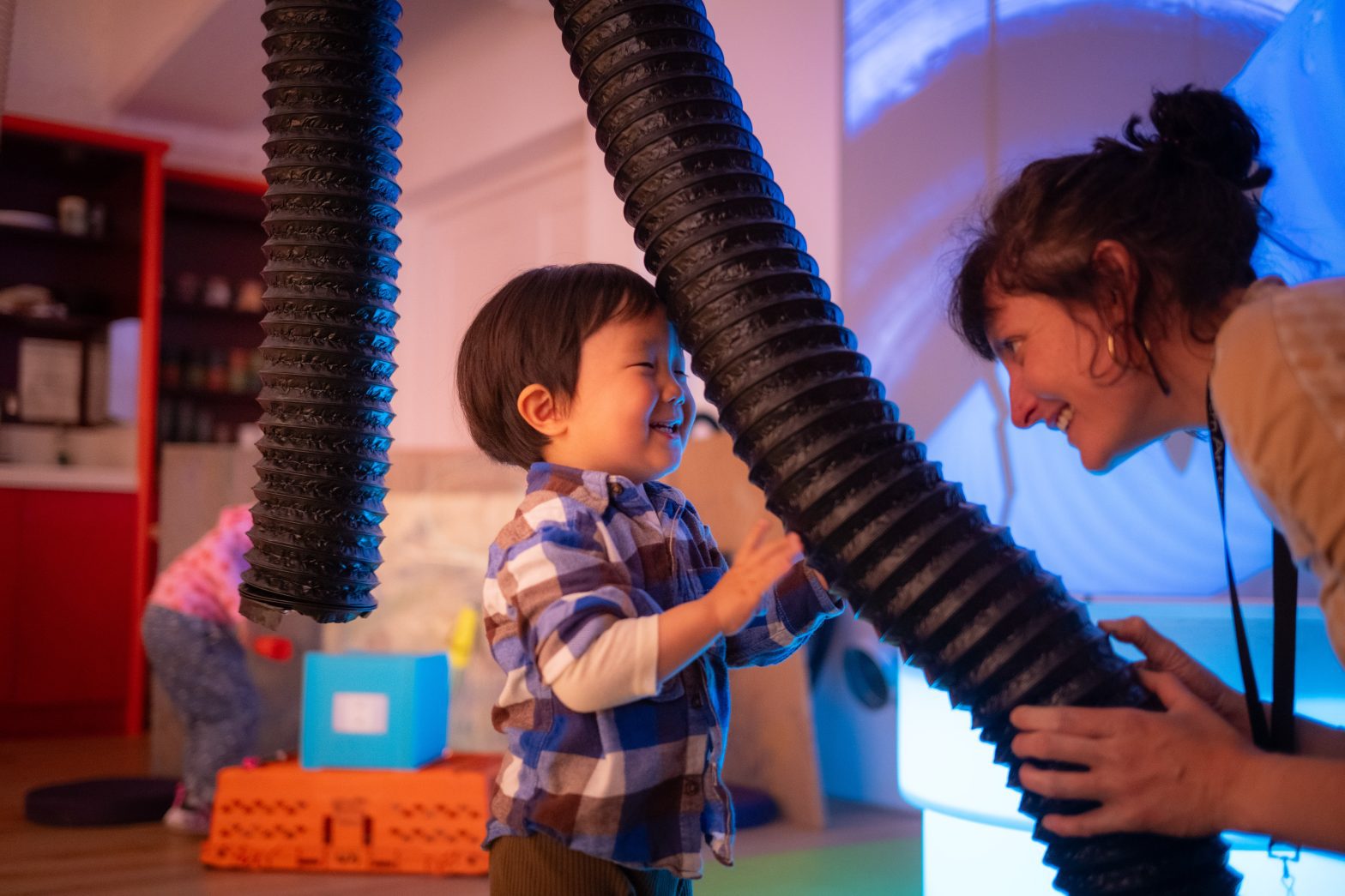 A woman holds a sculpture which a toddler touches.