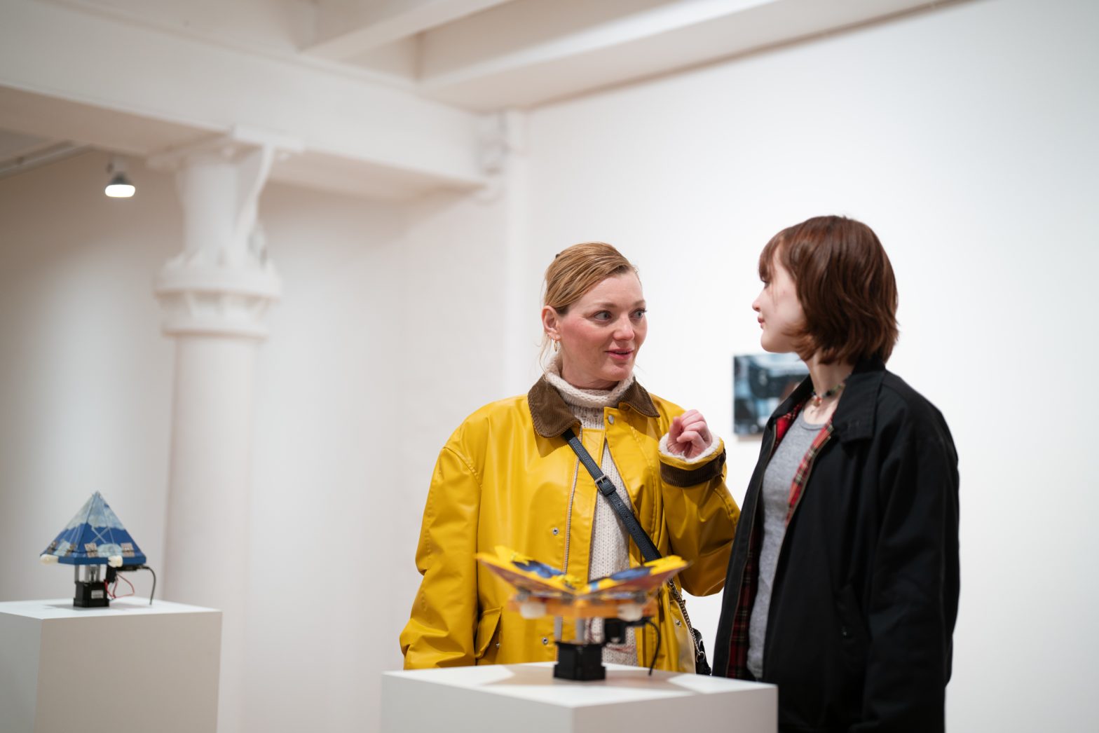 Two people talking in an art gallery.