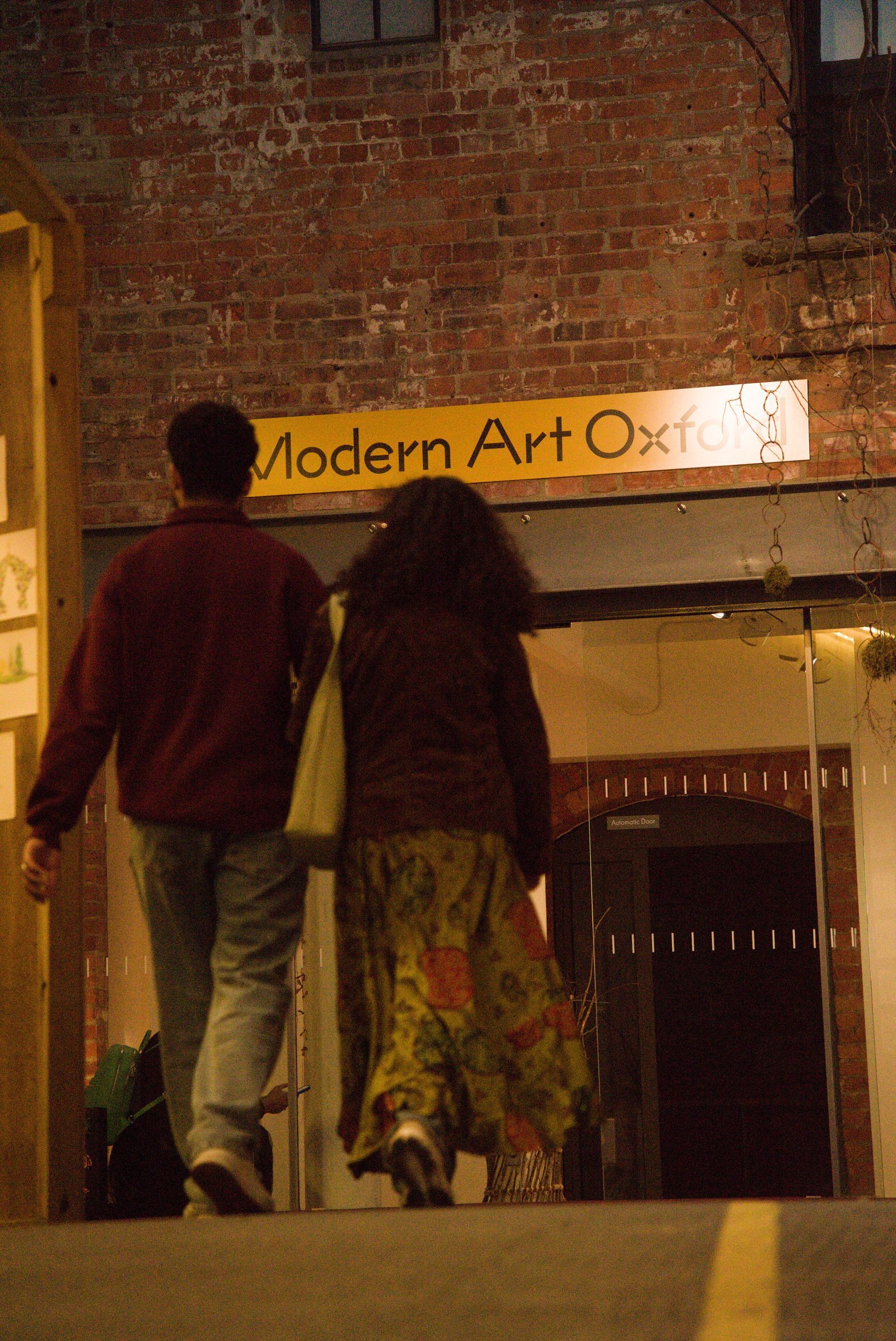 Two people are walking toward a building with a sign reading: Modern Art Oxford