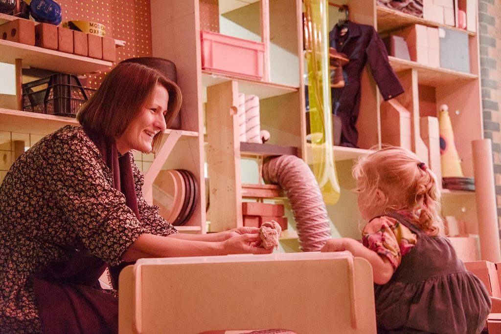 A photo of a mother and child playing in Modern Art Oxfords Studio. They are playing with kinetic sand and laughing.