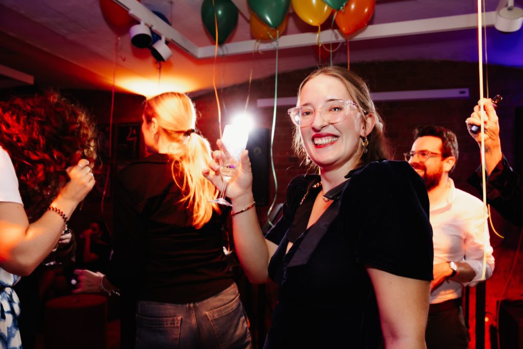 A girl is holding a glass of champagne at a party at Modern Art Oxford.
